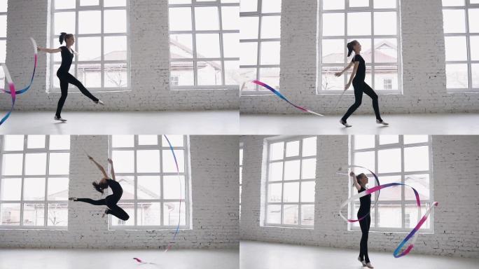 艺术体操的训练-十几岁的女孩在白色工作室或体操学校的背景大窗户上用彩带进行体操练习。穿着黑色身体的苗