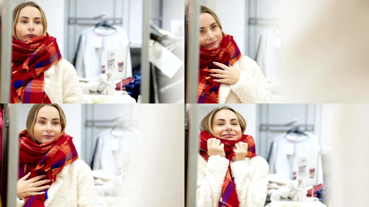 冬季购物的女人在照镜子时试戴围巾，微笑着在服装店里快乐地抱着