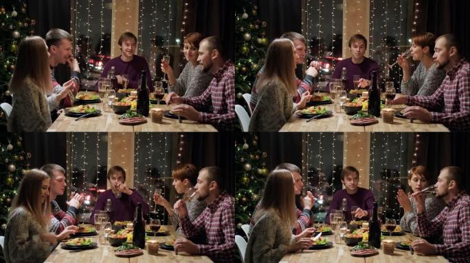 朋友假日聚会晚餐在家围桌吃饭。庆祝圣诞节。五个人吃饭，喝香槟，谈笑风声。