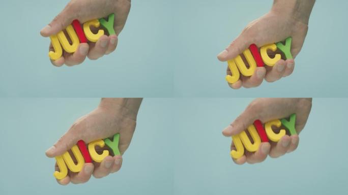 用五颜六色的塑料字母拼出的 “果汁” 一词被握在水下的手中。