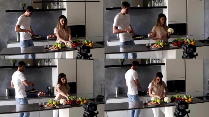 穿着便服的年轻迷人情侣博客拍摄关于他们日常生活方式的视频食物博客，在现代厨房用相机烹饪简单的早餐