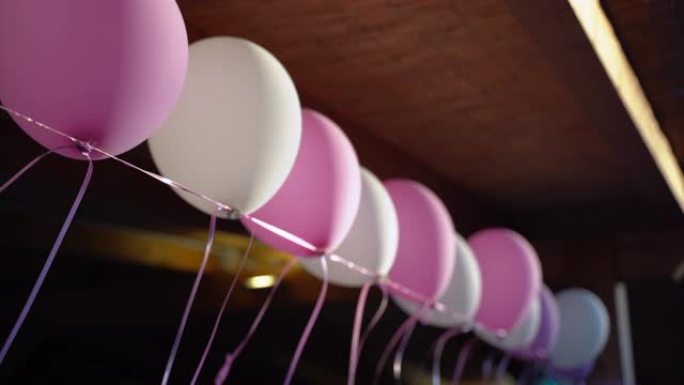 各种彩色氦气球装饰户外木屋。白色和粉红色的小气球在风的长绳上移动。庆祝气氛，难忘派对装饰品的创新理念