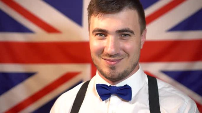 一个穿着领结和白衬衫的男人在英国国旗的背景上。