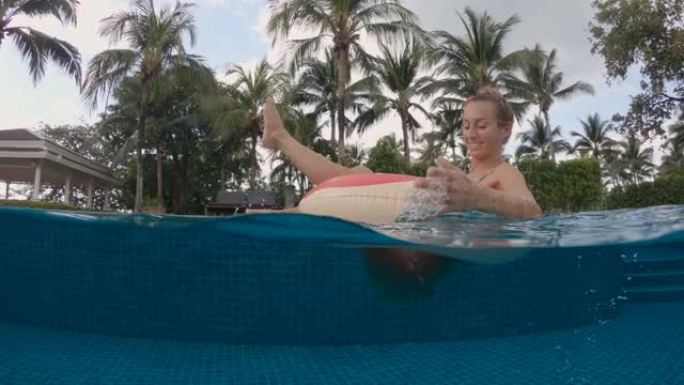 穿着比基尼在游泳池充气甜甜圈的暑假女人。在度假村游泳池享受旅游假期的女孩放松日光浴的景色。