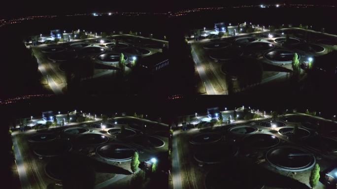 带圆形水池清洁污水的现代废水处理厂的空中夜景