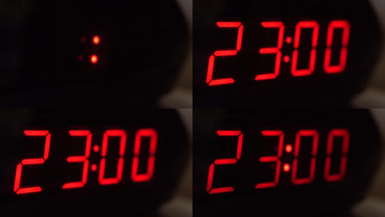 黑色数字时钟屏幕的特写显示23.00。黑色背景上闪烁红色数字。现代定时器系统和霓虹灯、电动报警装置