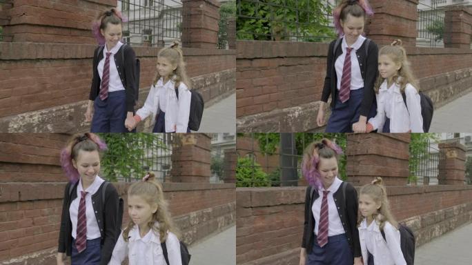 两个女孩姐妹牵手上学，穿着校服的孩子背着背包，背景城市街道