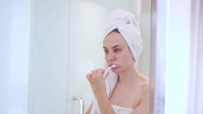 年轻漂亮的女人在浴室后刷牙