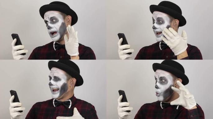 小丑化妆和视频聊天的可怕男人。恐怖小丑通过视频聊天与朋友交流。万圣节服装。