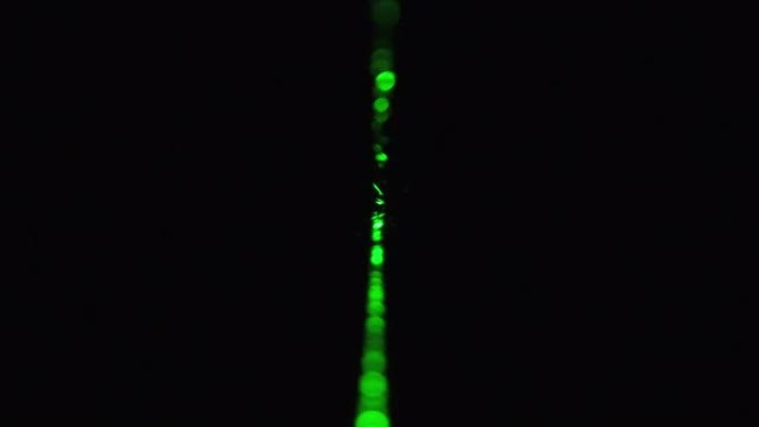 黑色背景上的绿色激光射线。功率激光束在雾中发光