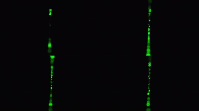 黑色背景上的绿色激光射线。功率激光束在雾中发光