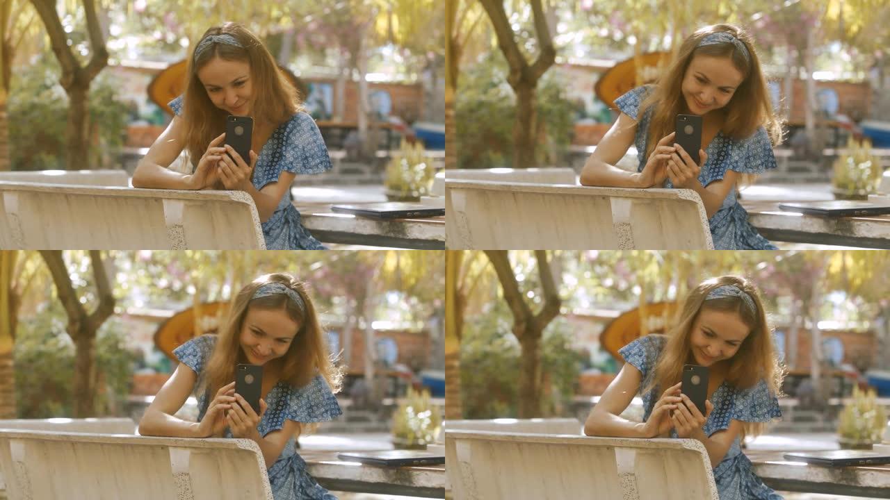 金发女孩在公园的桌子上张贴智能手机上的照片