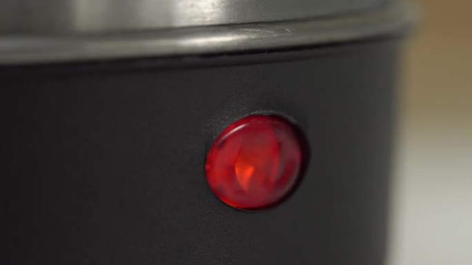 打开电热水壶时，红色灯会亮起。宏观，特写。