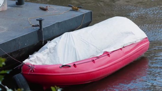 充气橡胶红船停泊在岸上，在不使用期间被覆盖。