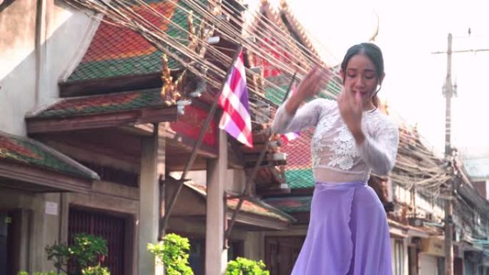 以下是前视图: 一位亚洲美丽的芭蕾舞演员，在泰国当地地标曼谷的泰式寺庙，以积极的情感和微笑在当地的城