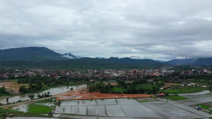 季风期间，在下雨天，老挝的Vang Vieng镇，森林和稻田被绿色的山脉包围。