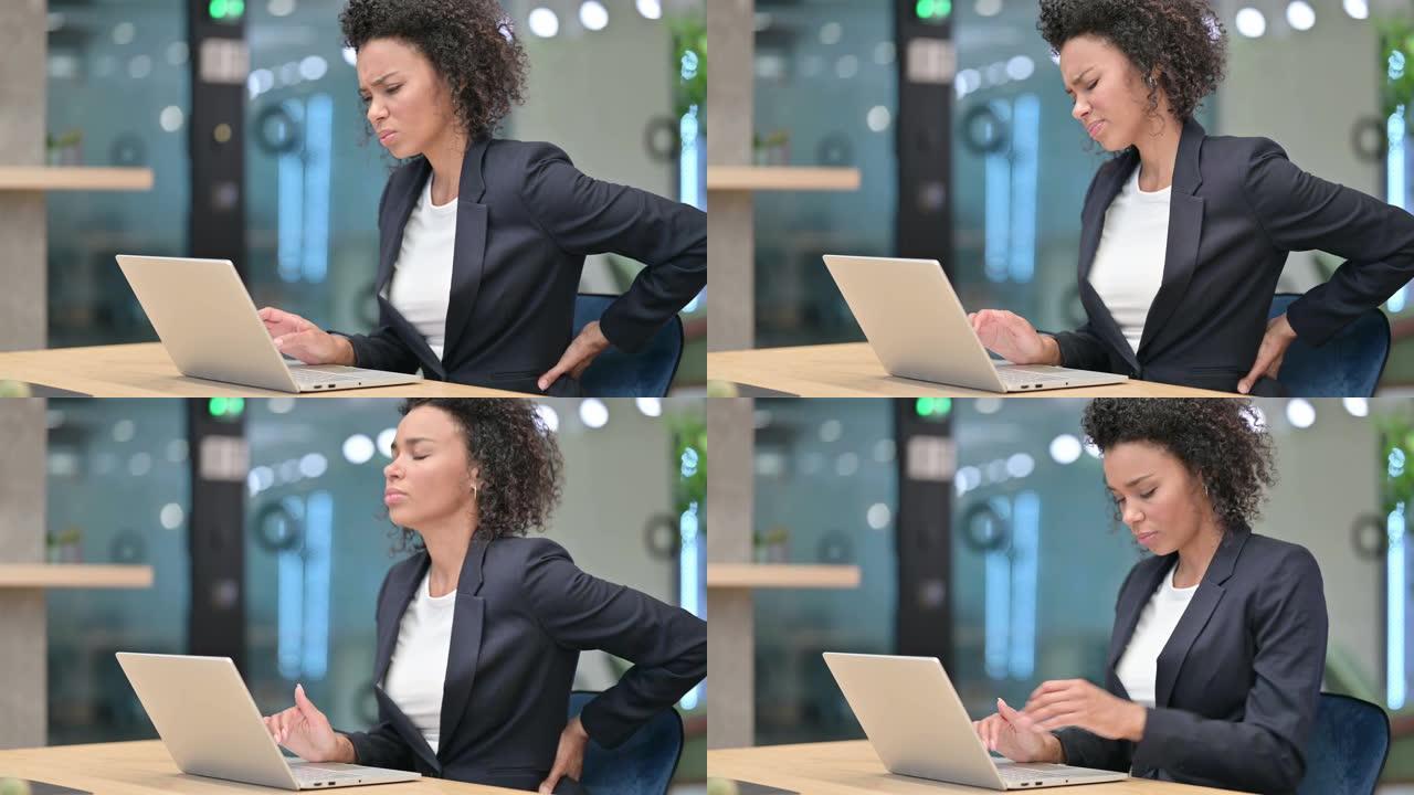 疲惫的非洲女商人，笔记本电脑在工作时背部疼痛