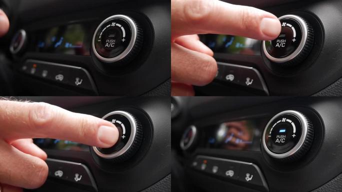 按下按钮打开汽车空调的特写镜头。男人的手转动按钮