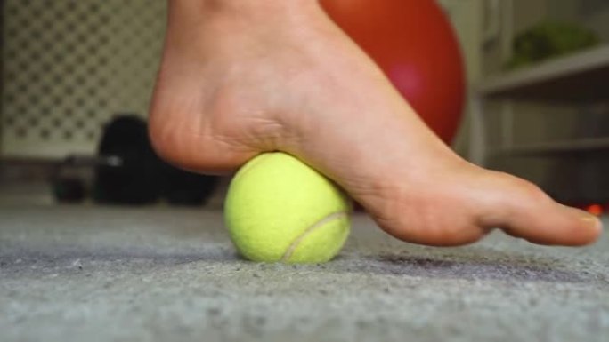 女人用网球按摩她的脚。