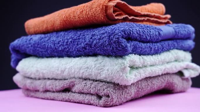 彩色毛巾堆的毛圈织物躺在粉红色的支架上