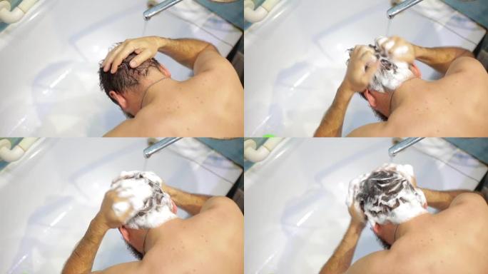 一名男子在水龙头下的浴室里洗头