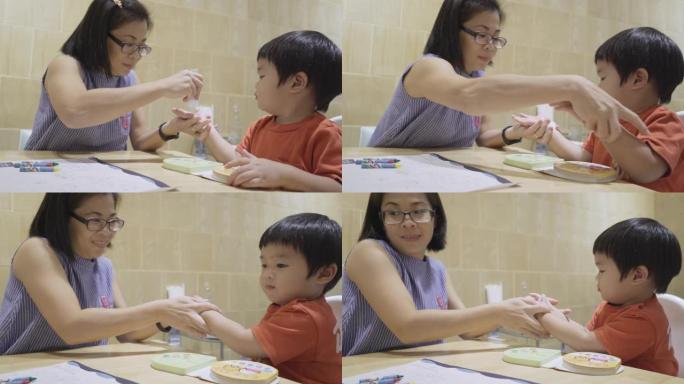 亚洲母亲在餐厅吃饭前用洗手液凝胶给儿子