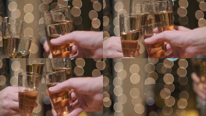 碰杯香槟。庆祝圣诞节。背景上有黄灯。很多手。一群朋友。