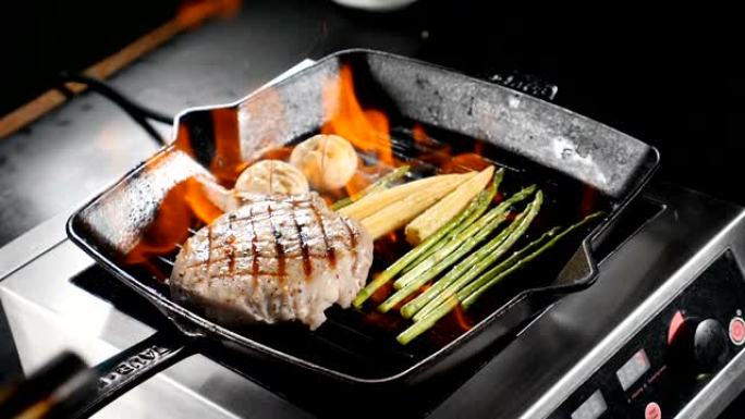 慢动作中的食物视频。专业厨师戴着蓝色手套，用火焰在煎锅上烹饪猪肉、牛排和酒精蔬菜。高清