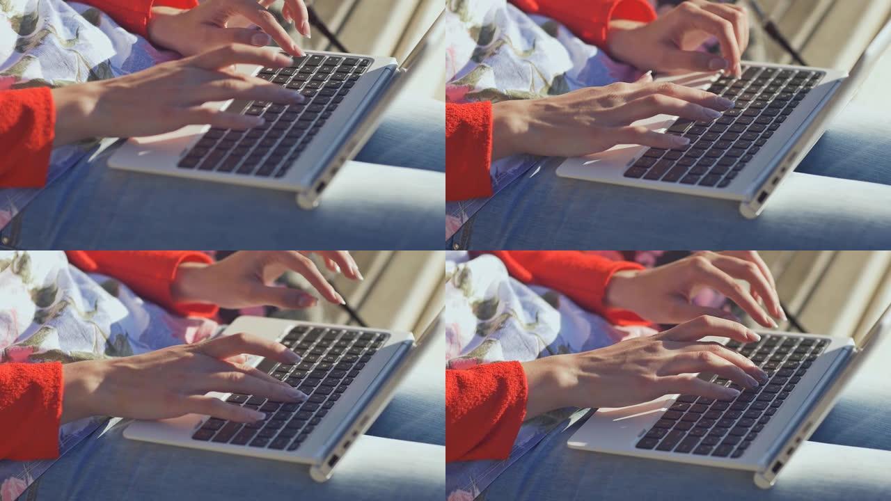 新鲜空气中的女孩在白色笔记本电脑的键盘上打字。年轻老练的女人在户外使用笔记本电脑