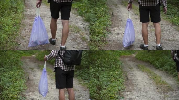 一个坏人从森林里的塑料垃圾袋里扔垃圾。雄性入侵者留下垃圾并走开。污染和生态问题，塑料回收，自然污染
