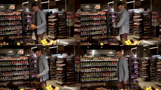 一个穿着蓝色衬衫的白人男子在一家杂货店超市的农产品部门购买水果和蔬菜。带着柚子，把它放进黑色的手提篮