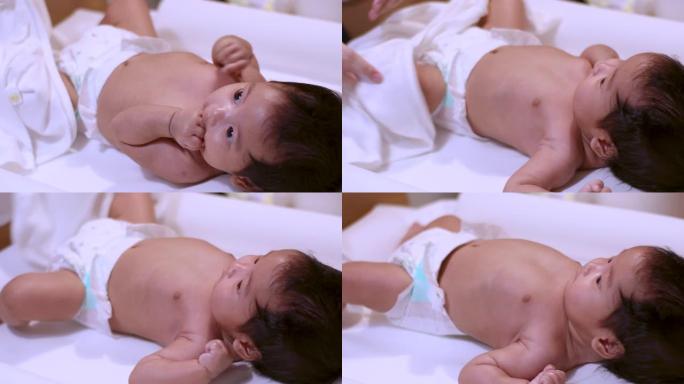 4k亚洲小婴儿女婴在家洗完澡后躺在白色桌子上，快乐，荧光灯，白天，纯真，婴儿护理，保重，育儿，卫生疗