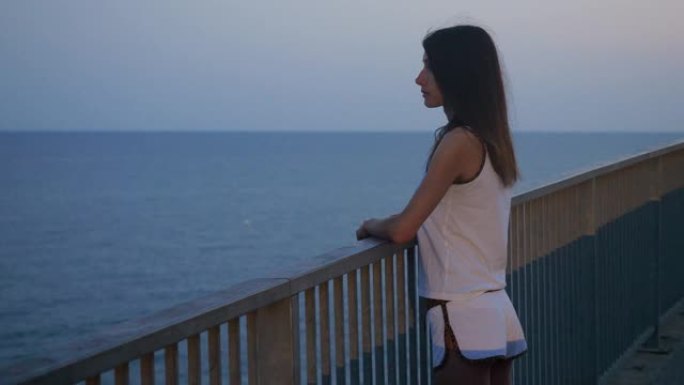 一个年轻漂亮的女人在日落时看着地中海。巴塞罗那。西班牙。4K