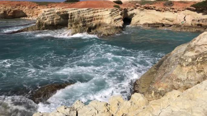 海浪拍打着岩石。晶莹剔透的大海，层层叠叠的岩石和美丽的大自然。蔚蓝的海滨。选择性聚焦