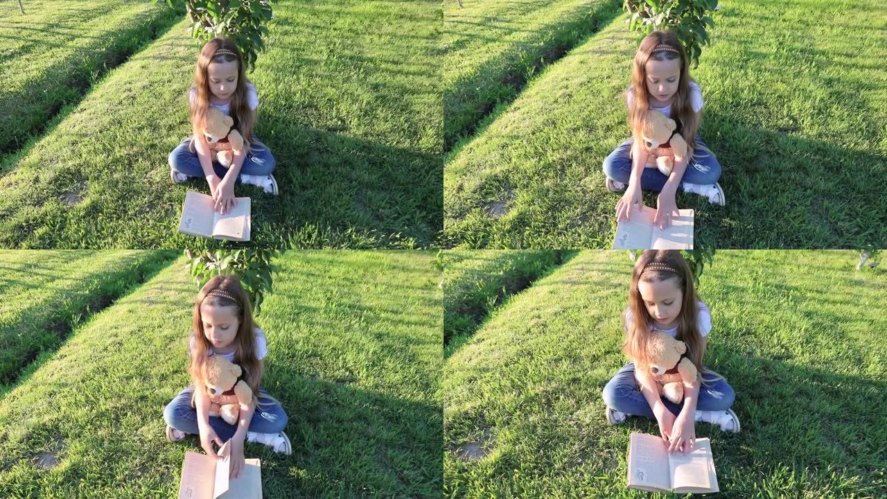 可爱的女孩在森林的草地上看书泰迪熊。森林里的花林间空地。一个孩子在花园里读一本泰迪熊