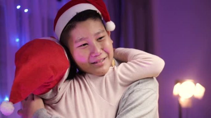 亚洲兄弟在家里的圣诞晚会上拥抱他的妹妹，爱和情感的概念。