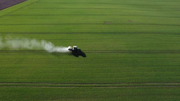 农用拖拉机在早春绿色作物田上撒肥，空中