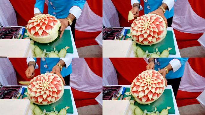 厨师在新鲜的西瓜上切花装饰。装饰西瓜雕刻