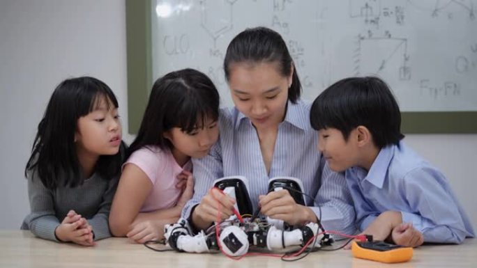 亚洲女教师在学校实验室教学和测试机器人反应。年轻的建筑师儿童设计和演示电路技术思想和协作开发机器人。