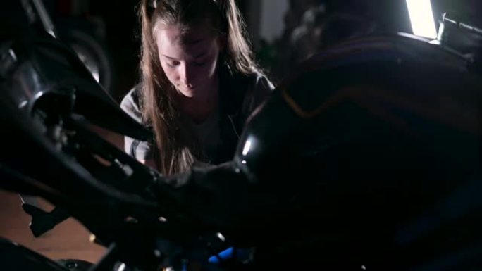 年轻女子在车库修理摩托车