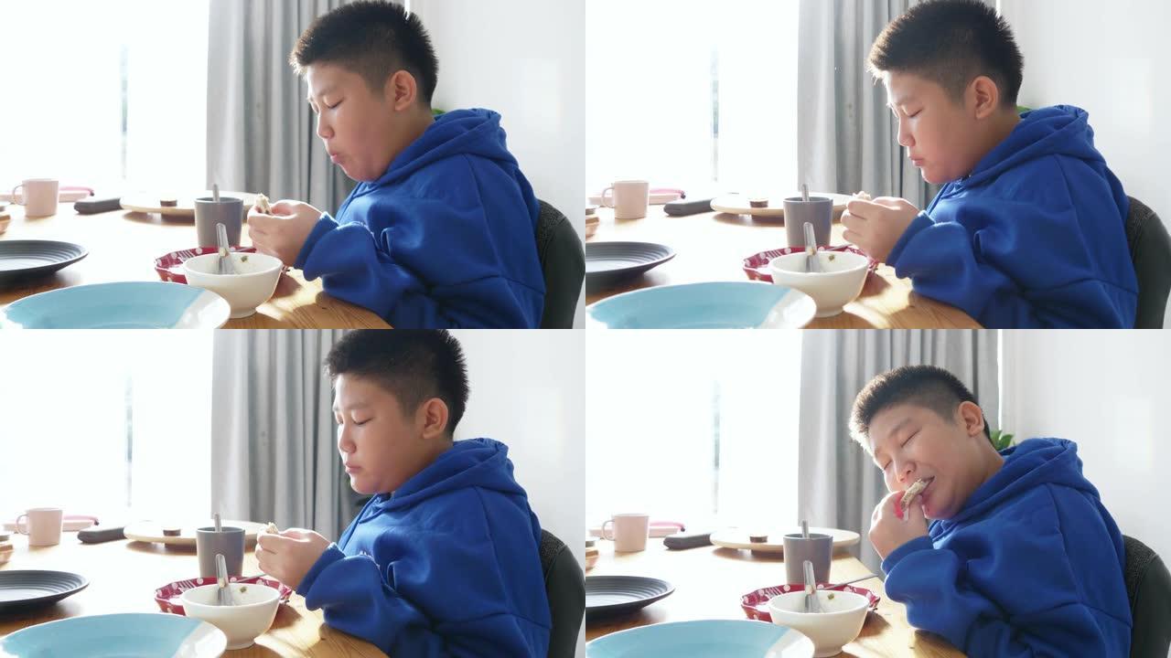 穿着蓝色兜帽的快乐亚洲男孩在上学前早上和妹妹一起吃早餐。