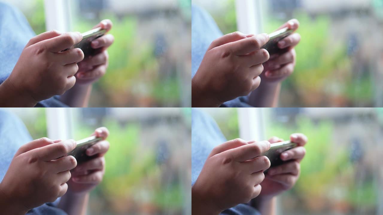 下雨天男孩用智能手机在家玩网络游戏。