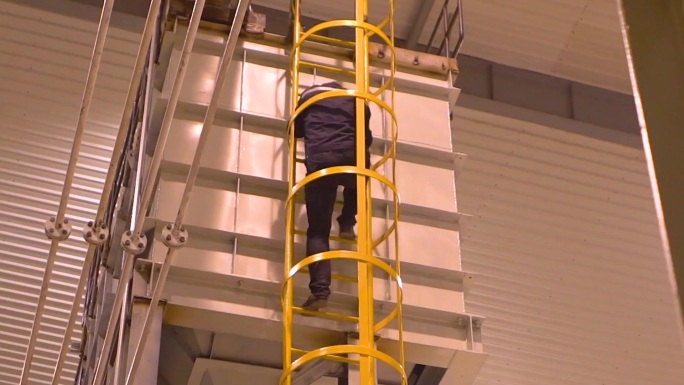 两个男人在机器前工作 一个男人正在仓库里爬梯子 工厂中的机器图片