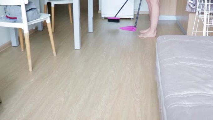 女人用刷子和dust打扫厨房地板