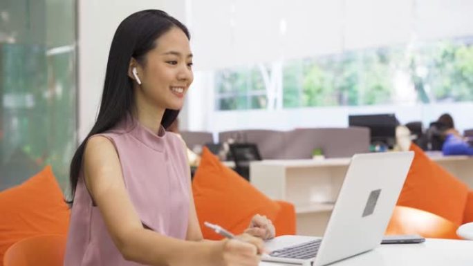 开朗的亚洲女商人与同事进行视频通话，在现代办公室戴耳机，幸福，创业，企业家