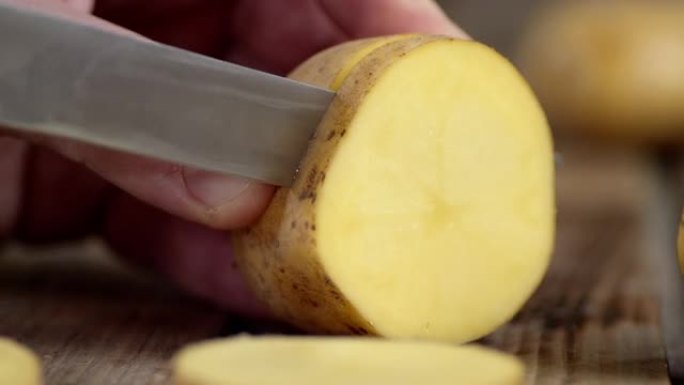 男性用刀将土豆切成碎片。