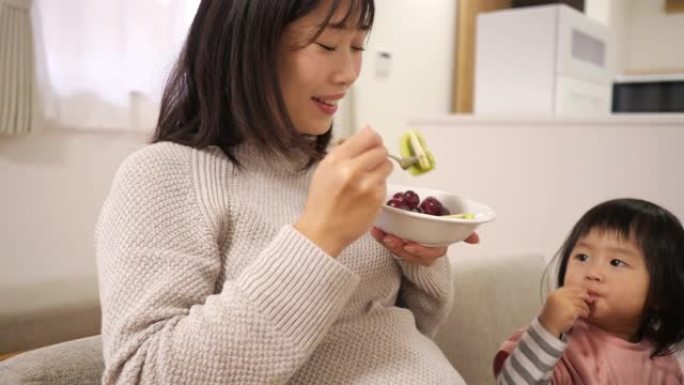 怀孕的母亲和她的小女儿在餐厅吃水果