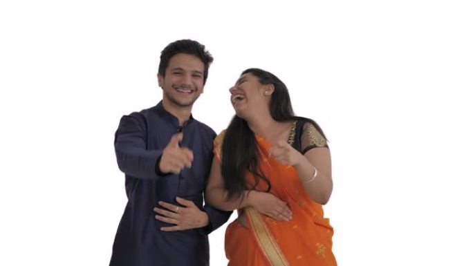 年轻的印度夫妇嘲笑某人，嘲笑并指向镜头。孤立在白色背景上。