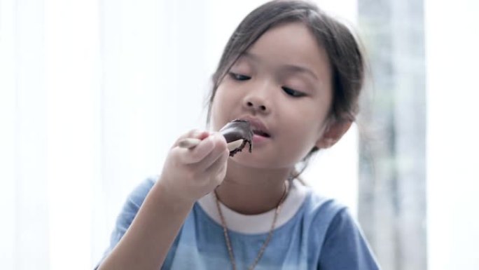 亚洲女孩在家一起在地板上吃巧克力纸杯蛋糕，生活方式理念。