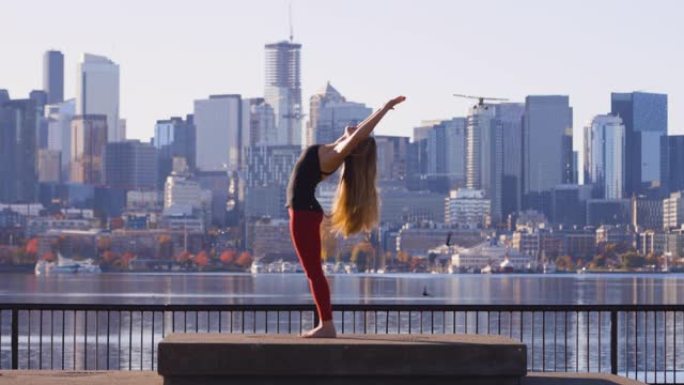 惊人的瑜伽射击女孩后弯伸展鸟类和飞机在西雅图华盛顿州天际线前飞行